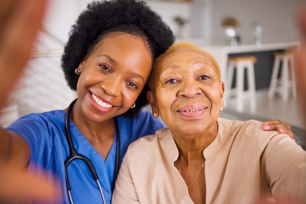 Black people, nurse and hug in elderly care for selfie, love or support and trust together at home. Black people, nurse and hug in elderly care for selfie, love or support and trust together at home
