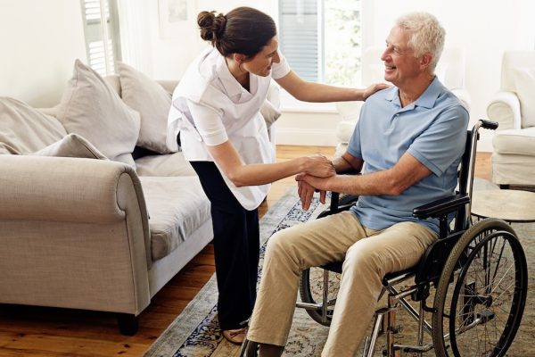 Shot of a caregiver helping a senior man in a wheelchair at home. Shot of a caregiver helping a senior man in a wheelchair at home.